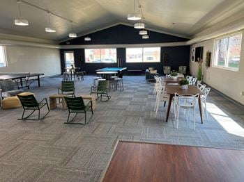 A large room with tables and chairs and a ping pong table